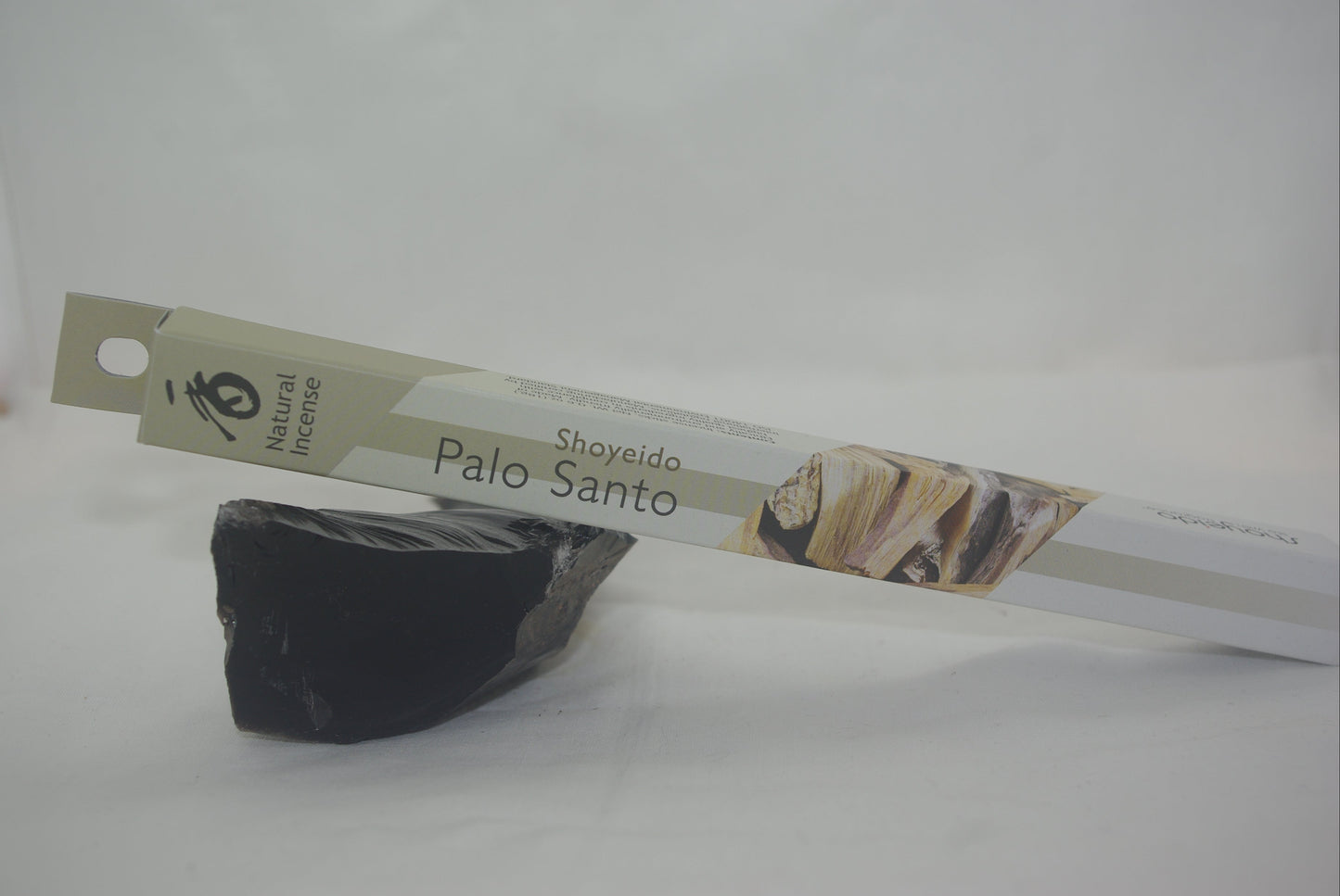 Black Palo Santo stone with a branded packaging strip on a white background