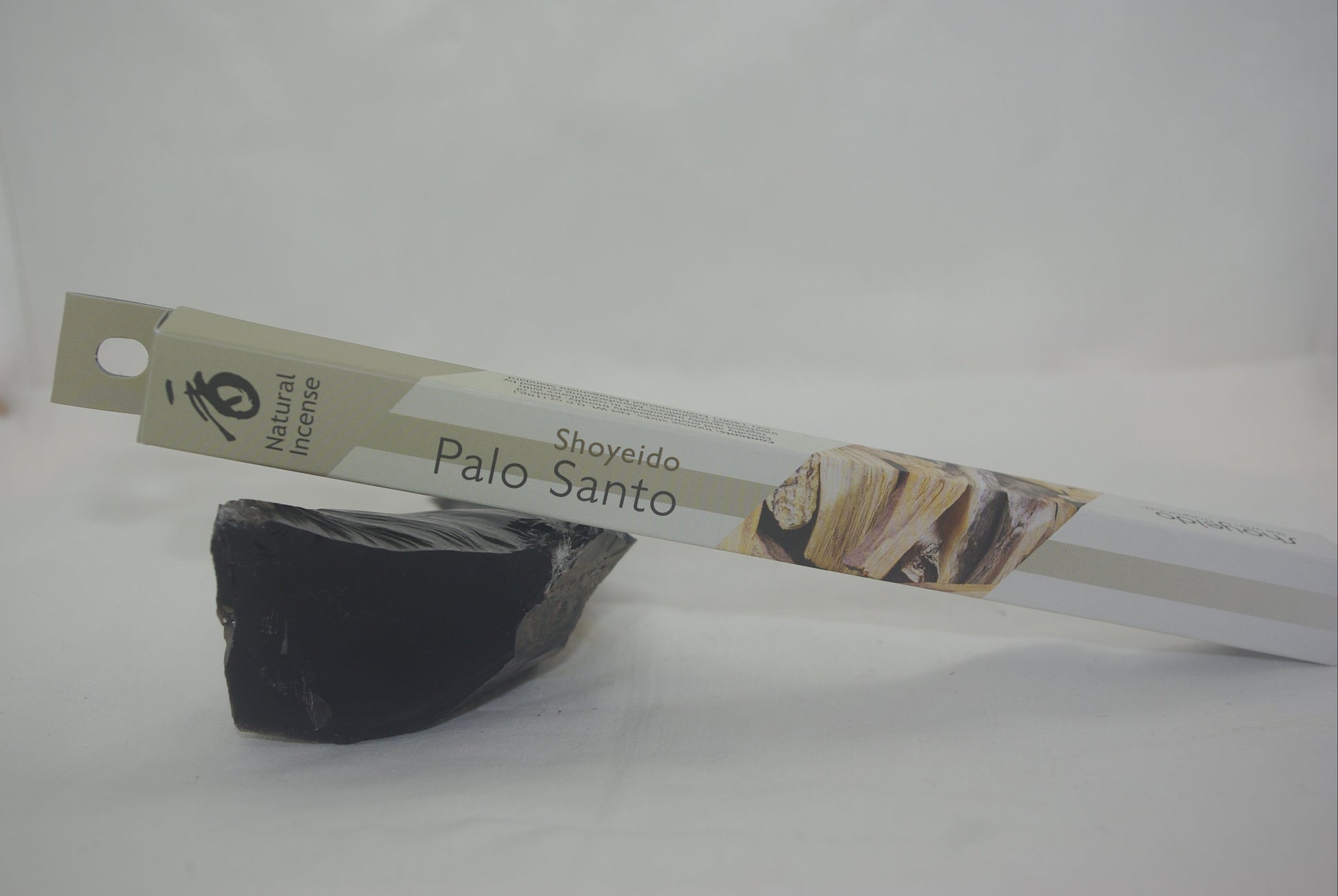 Black Palo Santo stone with a branded packaging strip on a white background